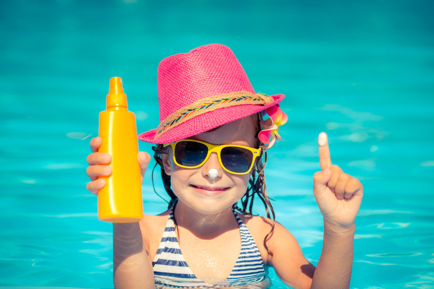 girl holding sunscreen on a bright sunny day