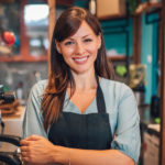 Portrait of a beautiful waitress wearing an apron, smiling at camera.