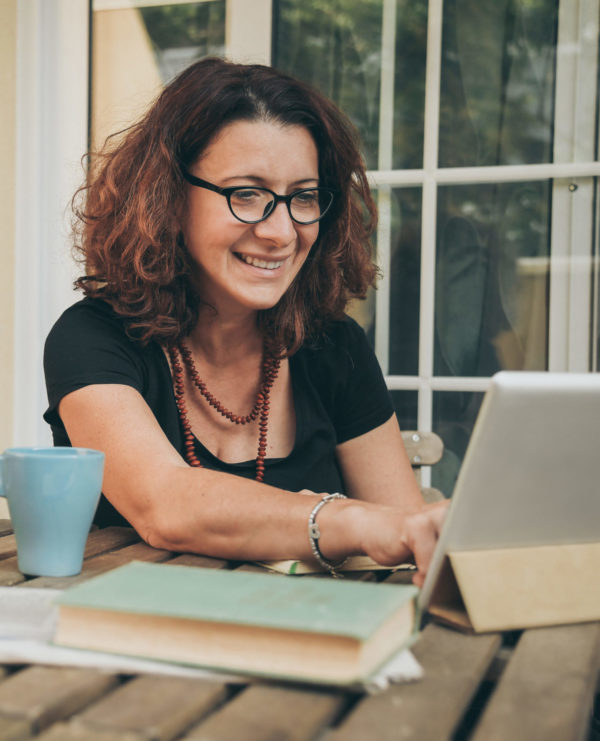 woman smiling while working online with a tablet