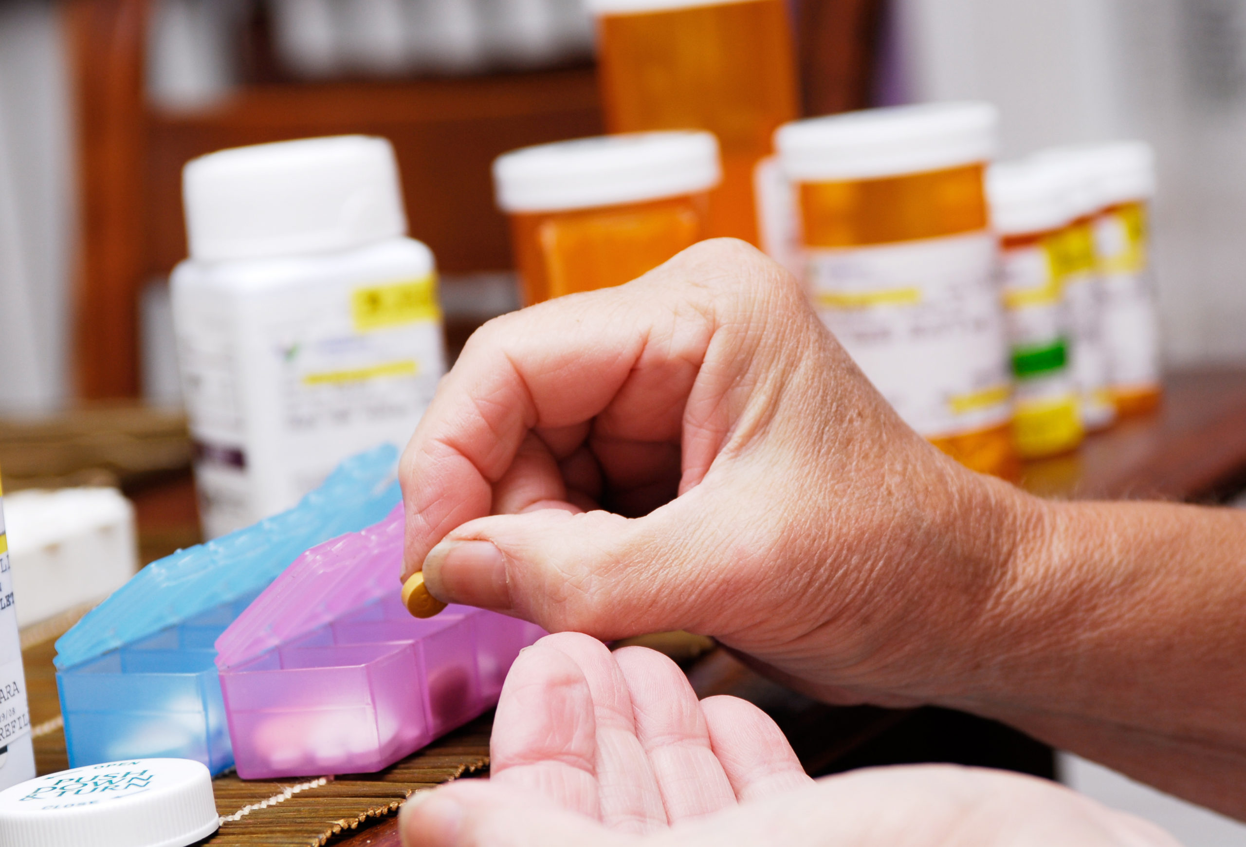 Woman using an organized pill box to take medication as prescribed.