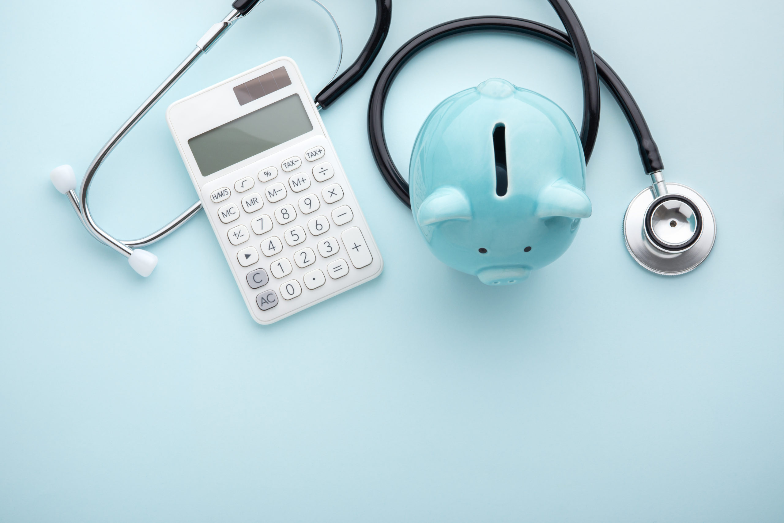 Piggy bank with stethoscope and calculator on blue background, health insurance, tax concept, with space