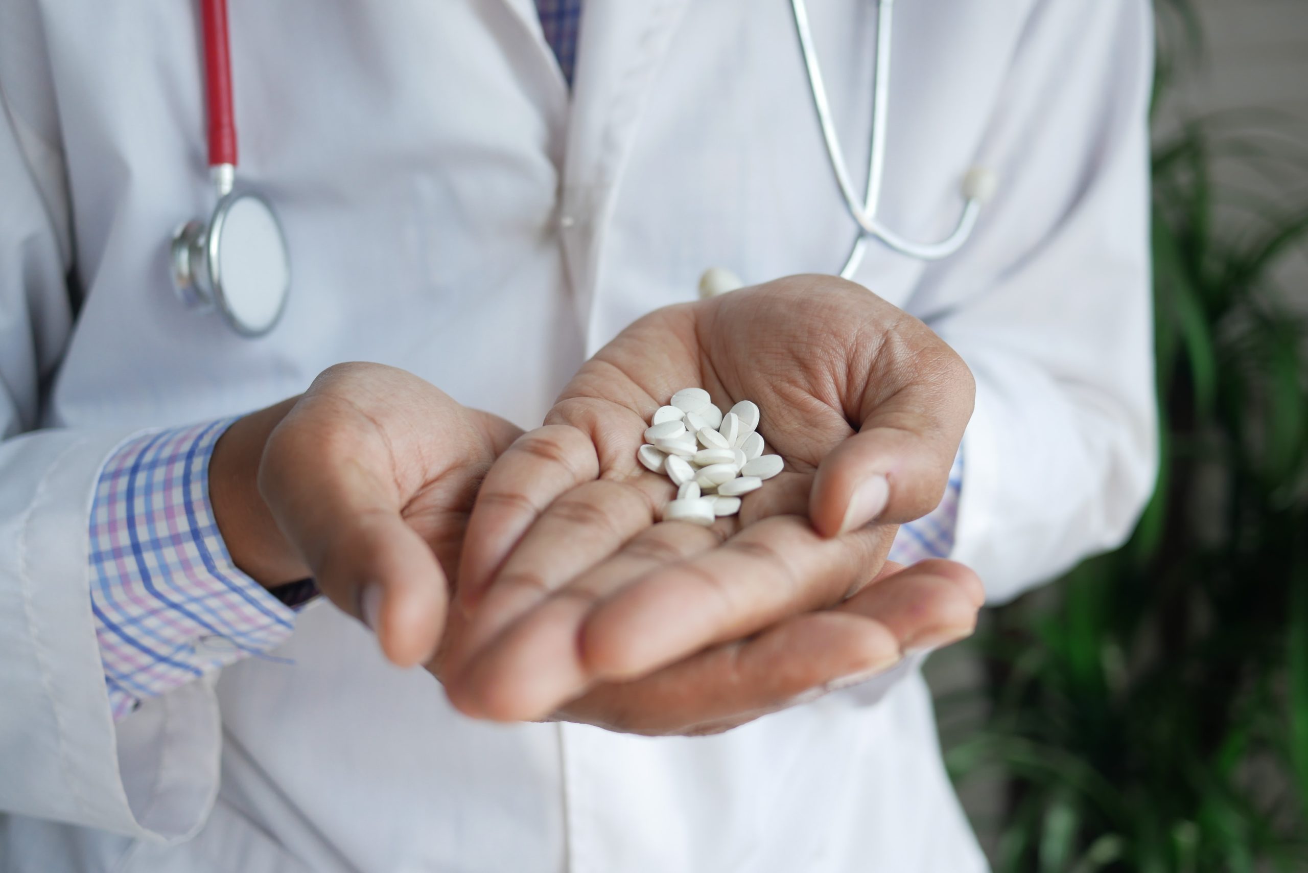 doctor holding several white gabapentin pills in the palm of hand
